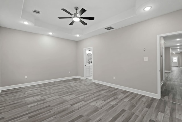 spare room featuring wood-type flooring, a raised ceiling, and ceiling fan