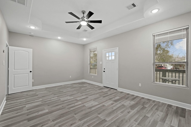 entryway featuring ceiling fan, light hardwood / wood-style floors, and a tray ceiling