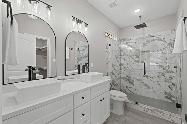 bathroom with a shower with door, vanity, and toilet