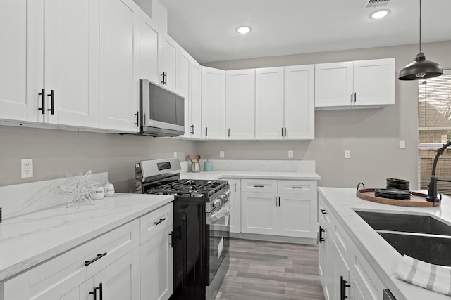 kitchen with appliances with stainless steel finishes, recessed lighting, white cabinets, and decorative light fixtures