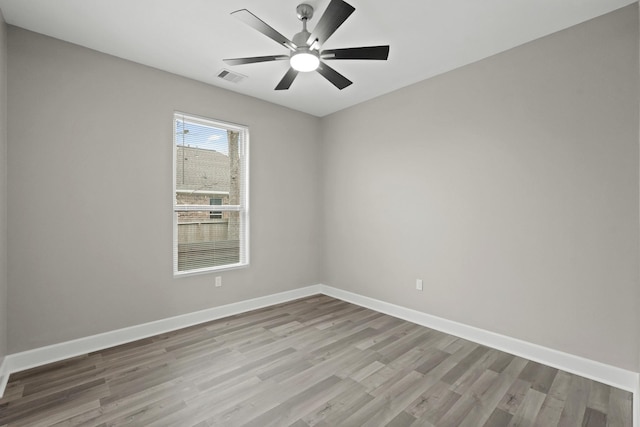 empty room with light wood finished floors, baseboards, visible vents, and a ceiling fan