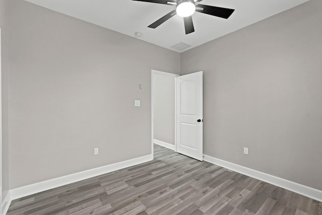 empty room featuring ceiling fan, baseboards, and wood finished floors