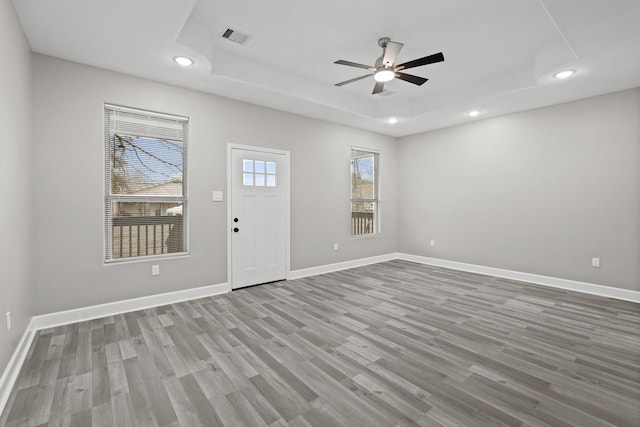 foyer entrance featuring a raised ceiling, ceiling fan, and light hardwood / wood-style floors