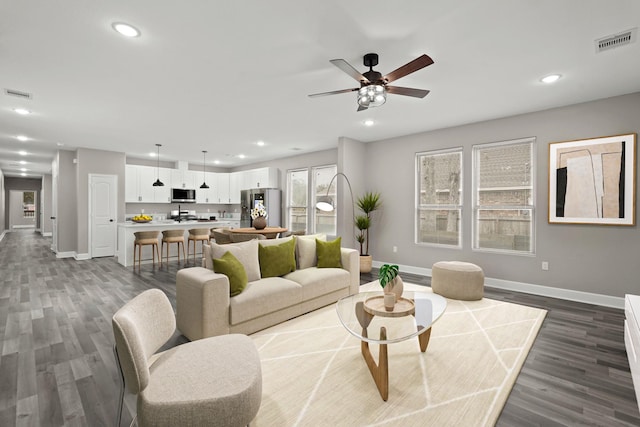 living room featuring ceiling fan and dark wood-type flooring