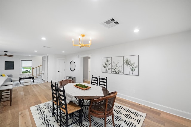 dining area featuring ceiling fan with notable chandelier and light wood-type flooring