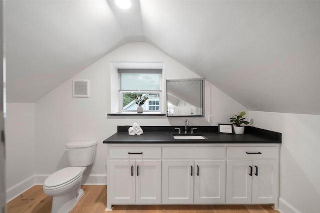 bathroom featuring hardwood / wood-style floors, vanity, vaulted ceiling, and toilet