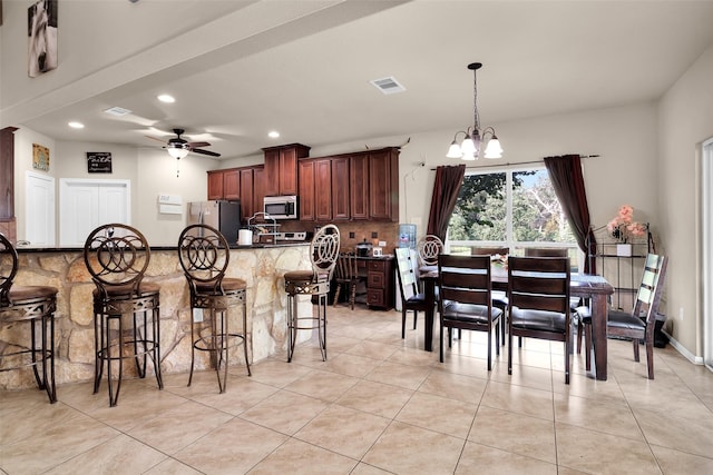 kitchen with ceiling fan with notable chandelier, light tile patterned floors, appliances with stainless steel finishes, tasteful backsplash, and decorative light fixtures