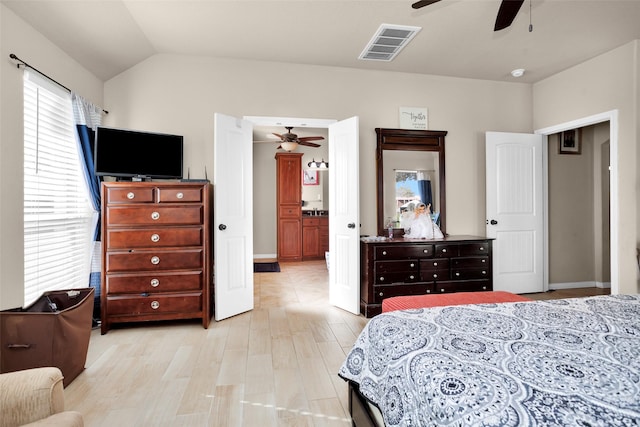 bedroom featuring ceiling fan, lofted ceiling, ensuite bathroom, and light hardwood / wood-style flooring