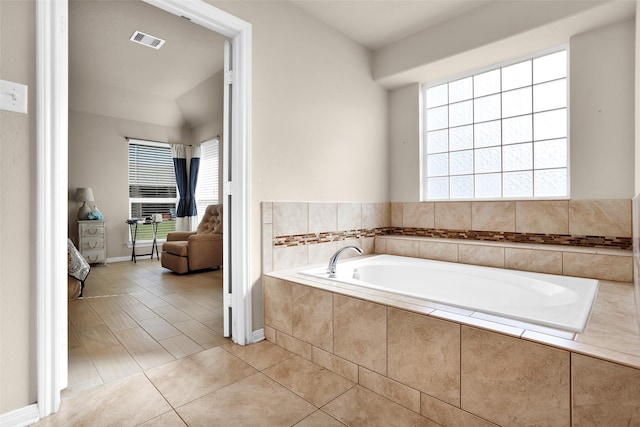 bathroom featuring tile patterned floors, a relaxing tiled tub, and lofted ceiling