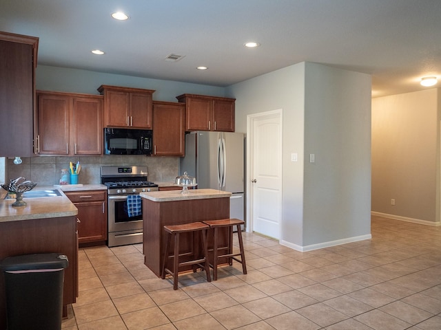 kitchen with backsplash, a breakfast bar, stainless steel appliances, light tile patterned floors, and a center island