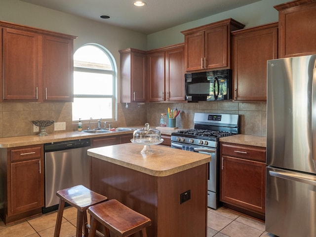 kitchen featuring light tile patterned flooring, sink, appliances with stainless steel finishes, a kitchen island, and a breakfast bar area