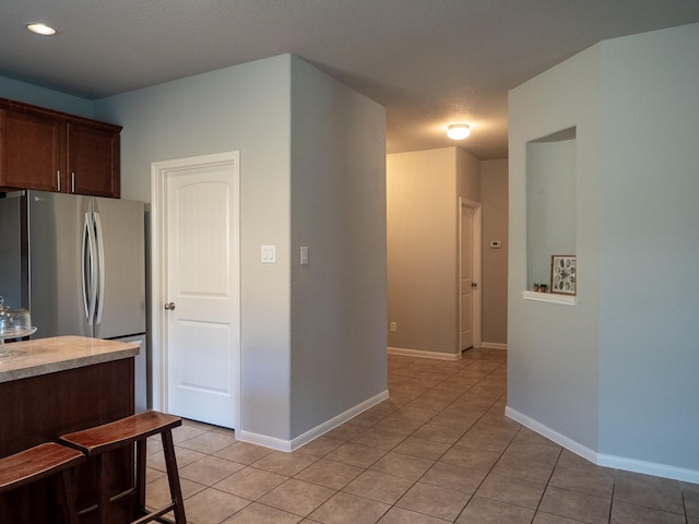 kitchen with stainless steel fridge, light tile patterned floors, and a textured ceiling