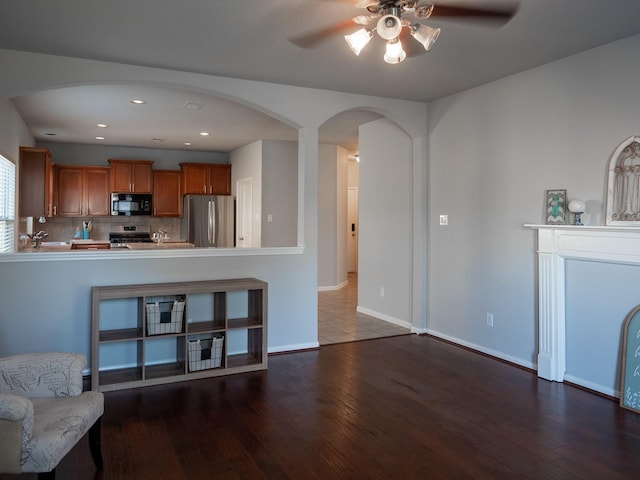 kitchen featuring stainless steel refrigerator, dark hardwood / wood-style flooring, backsplash, kitchen peninsula, and stove