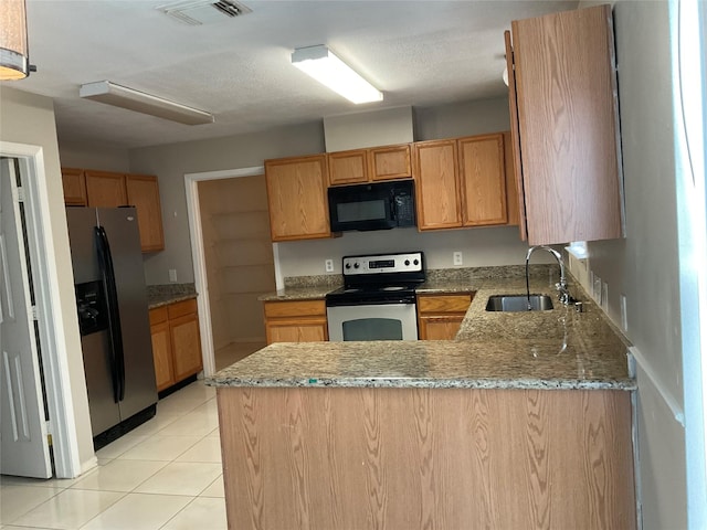 kitchen with sink, light stone countertops, light tile patterned floors, appliances with stainless steel finishes, and kitchen peninsula