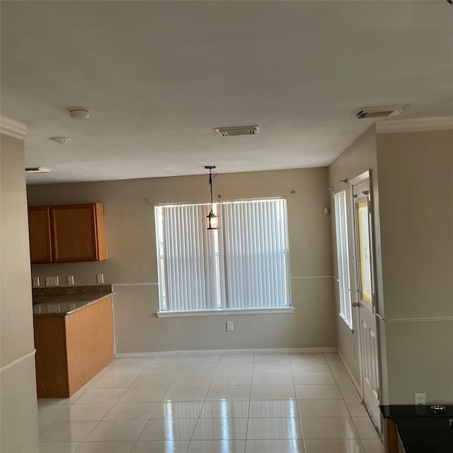 kitchen featuring crown molding, light tile patterned floors, and decorative light fixtures