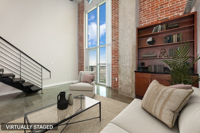 living room featuring a towering ceiling and brick wall