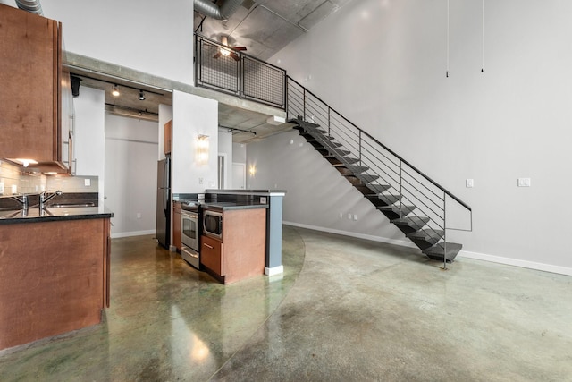 kitchen featuring a high ceiling, track lighting, appliances with stainless steel finishes, and sink