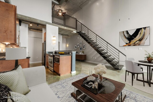 living room featuring a towering ceiling, rail lighting, and ceiling fan