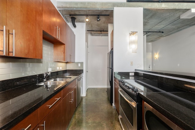 kitchen with track lighting, sink, decorative backsplash, dark stone countertops, and appliances with stainless steel finishes