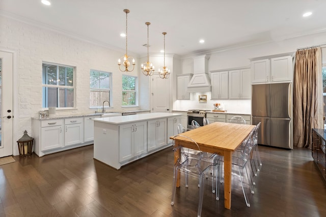 kitchen with white cabinetry, stainless steel appliances, decorative light fixtures, a kitchen island, and custom range hood