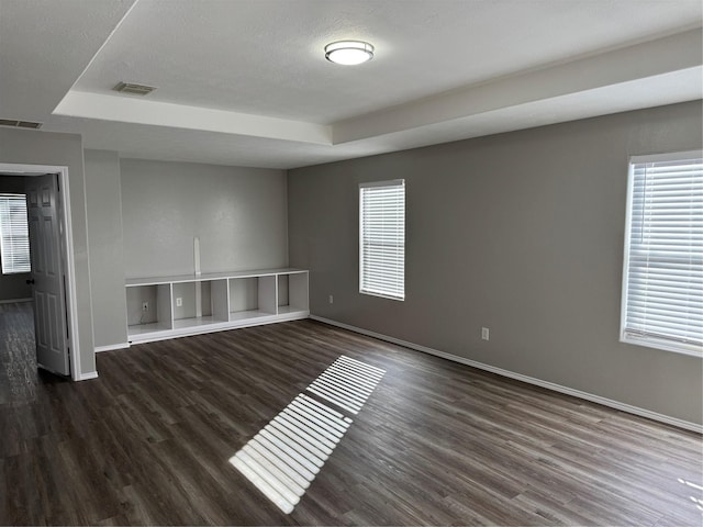 spare room featuring dark hardwood / wood-style flooring and a raised ceiling