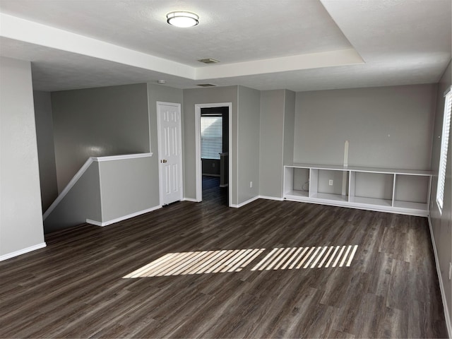 unfurnished room with a tray ceiling and dark hardwood / wood-style flooring