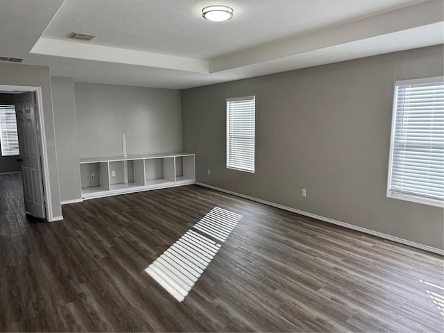 empty room with a tray ceiling and dark wood-type flooring