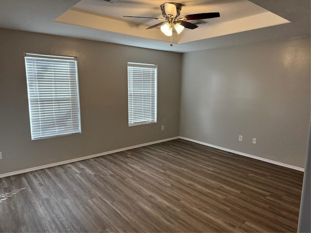 spare room featuring ceiling fan, a raised ceiling, and dark wood-type flooring