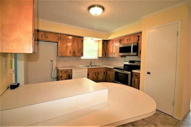 kitchen with sink, appliances with stainless steel finishes, a textured ceiling, light tile patterned flooring, and ornamental molding