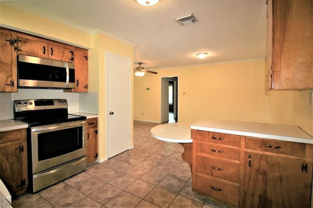 kitchen featuring ceiling fan, ornamental molding, a textured ceiling, kitchen peninsula, and stainless steel appliances