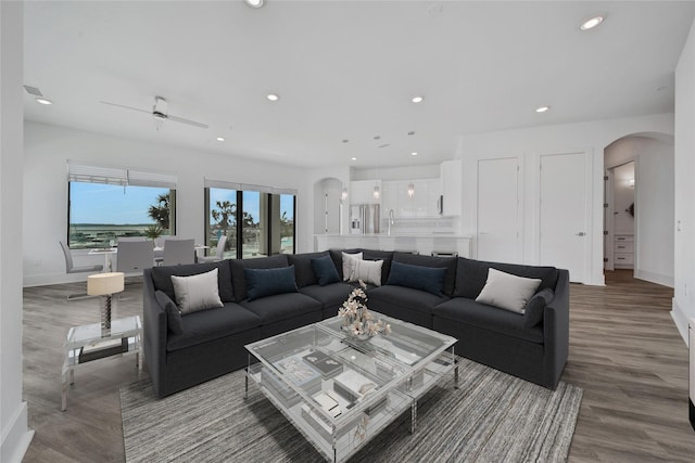 living room with hardwood / wood-style flooring, ceiling fan, and sink