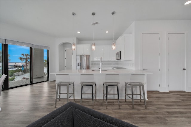 kitchen featuring white cabinetry, sink, decorative light fixtures, a breakfast bar, and appliances with stainless steel finishes