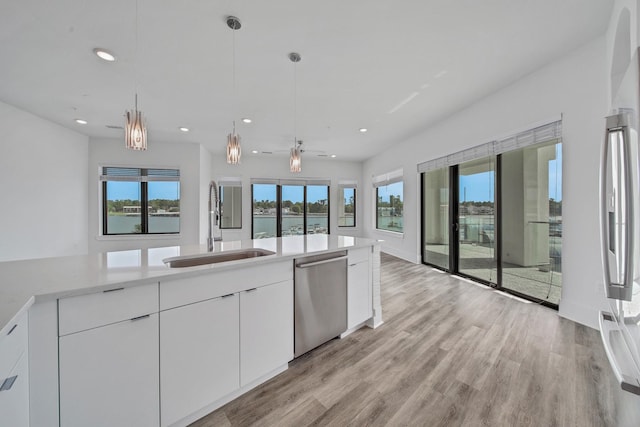 kitchen featuring white cabinets, pendant lighting, stainless steel dishwasher, and sink