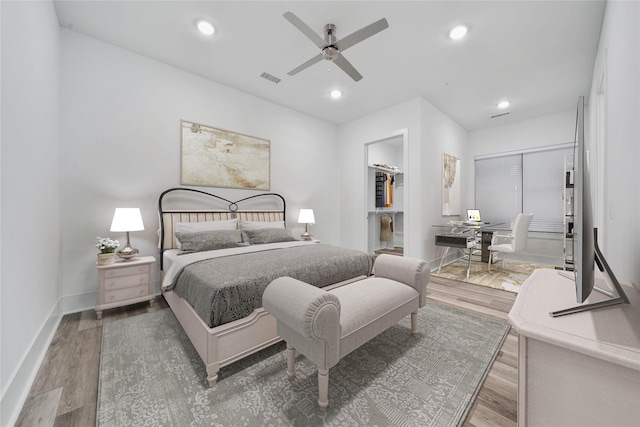 bedroom with wood-type flooring, a closet, a spacious closet, and ceiling fan