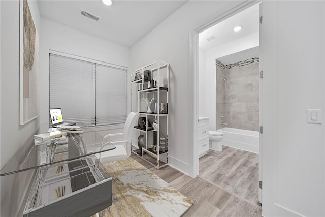 bathroom featuring toilet, hardwood / wood-style floors, and tiled shower / bath