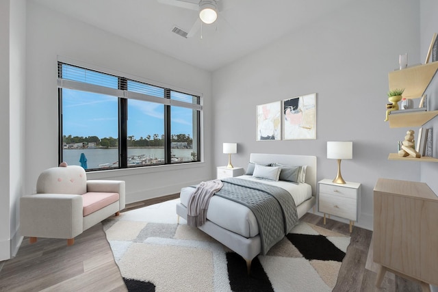 bedroom featuring ceiling fan, a water view, and hardwood / wood-style flooring