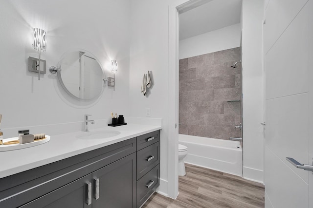 full bathroom with vanity, wood-type flooring, tiled shower / bath combo, and toilet