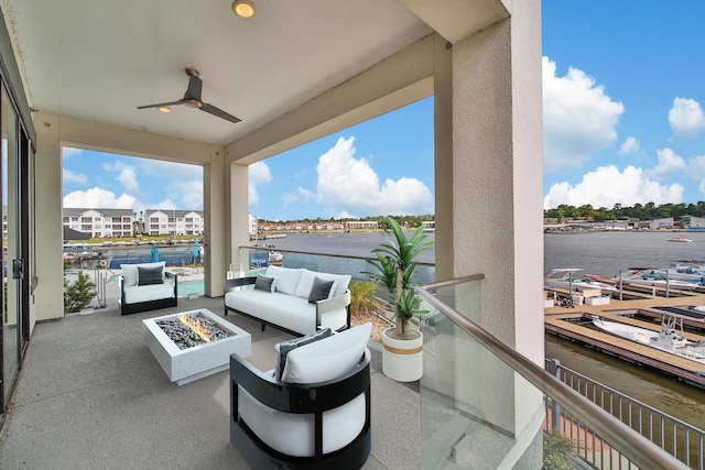 view of patio / terrace with ceiling fan, a water view, and an outdoor living space with a fire pit