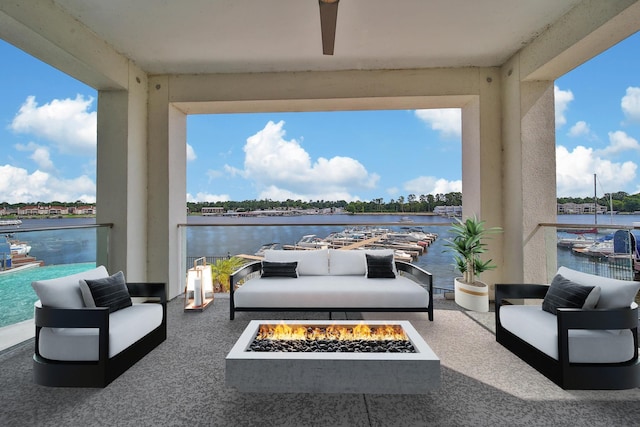 view of patio featuring ceiling fan, a water view, and an outdoor living space with a fire pit