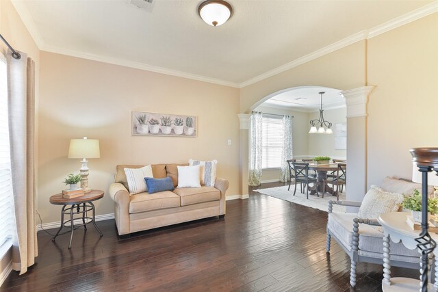 living room featuring a chandelier, dark hardwood / wood-style flooring, crown molding, and decorative columns