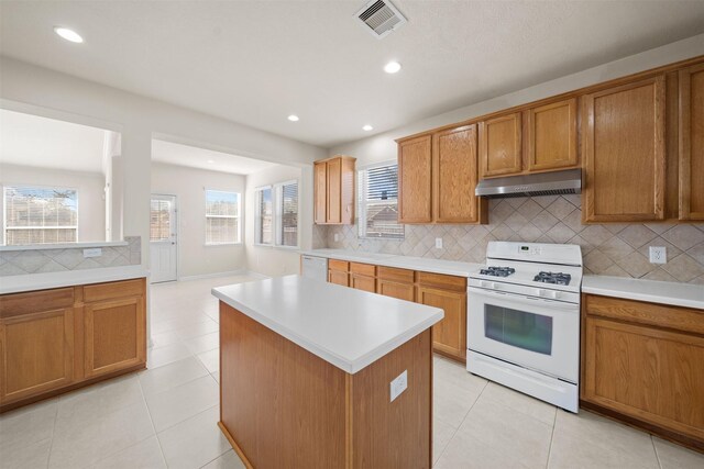 kitchen with light tile patterned floors, a wealth of natural light, white appliances, and a kitchen island