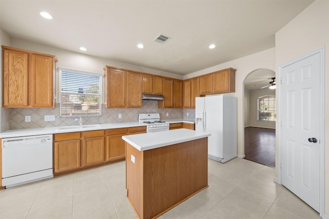 kitchen with white appliances, a center island, sink, ceiling fan, and light tile patterned floors