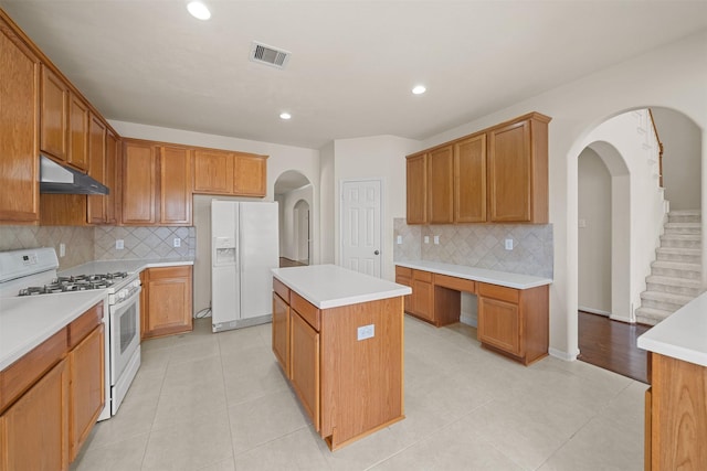 kitchen with light tile patterned flooring, a kitchen island, backsplash, and white appliances