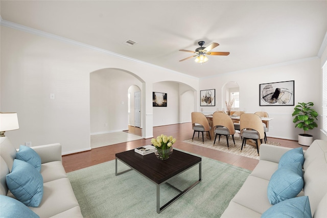 living room featuring ceiling fan, wood-type flooring, and ornamental molding