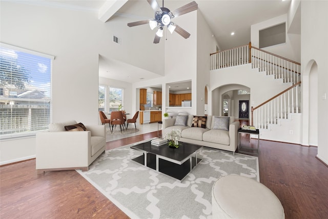 living room featuring a high ceiling, ceiling fan, hardwood / wood-style floors, and beamed ceiling