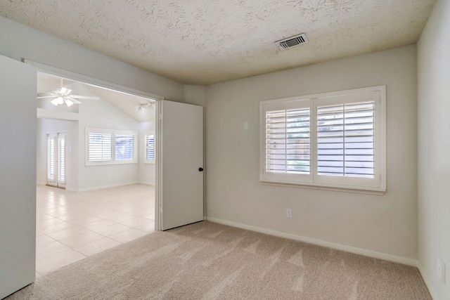 empty room featuring lofted ceiling, ceiling fan, light carpet, and a textured ceiling