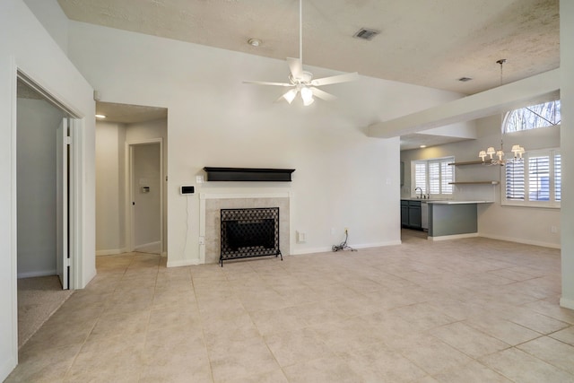 unfurnished living room featuring a tile fireplace, sink, lofted ceiling, light tile patterned floors, and ceiling fan with notable chandelier