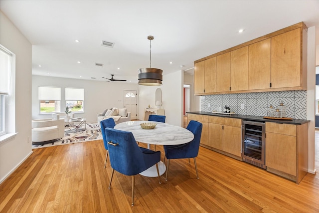 kitchen featuring light wood-type flooring, backsplash, ceiling fan, decorative light fixtures, and wine cooler