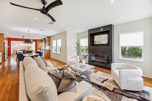 living room featuring ceiling fan, sink, and light hardwood / wood-style floors