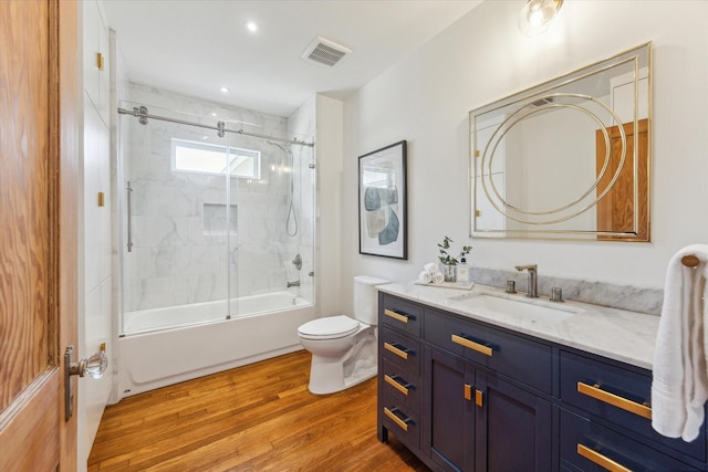 full bathroom with hardwood / wood-style floors, vanity, enclosed tub / shower combo, and toilet